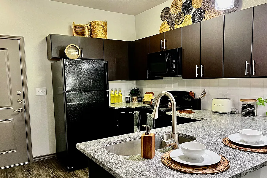 Contemporary kitchen with sleek black appliances, elegant countertops, and stylish decor baskets.