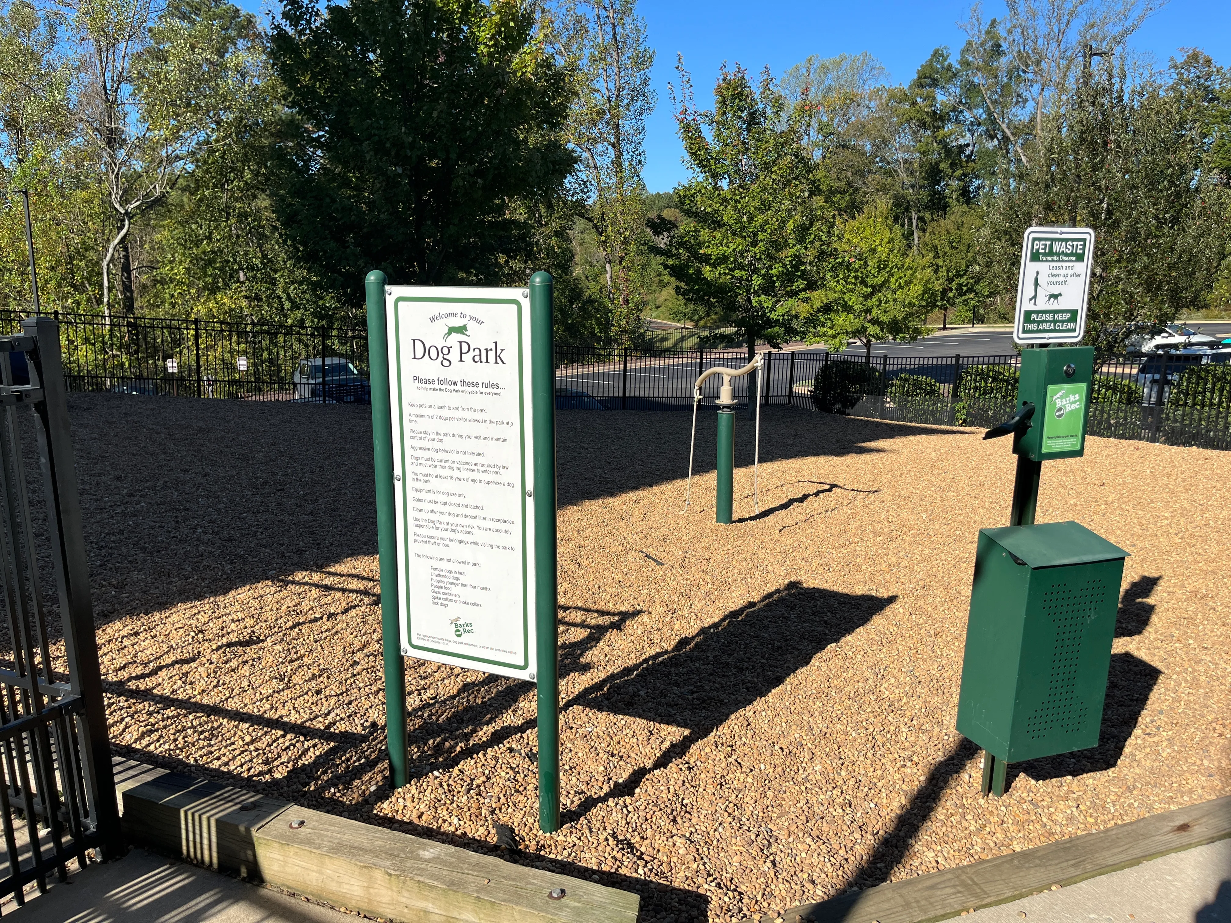 Inviting dog park with ample space for pets to play, surrounded by lush trees and convenient waste stations.