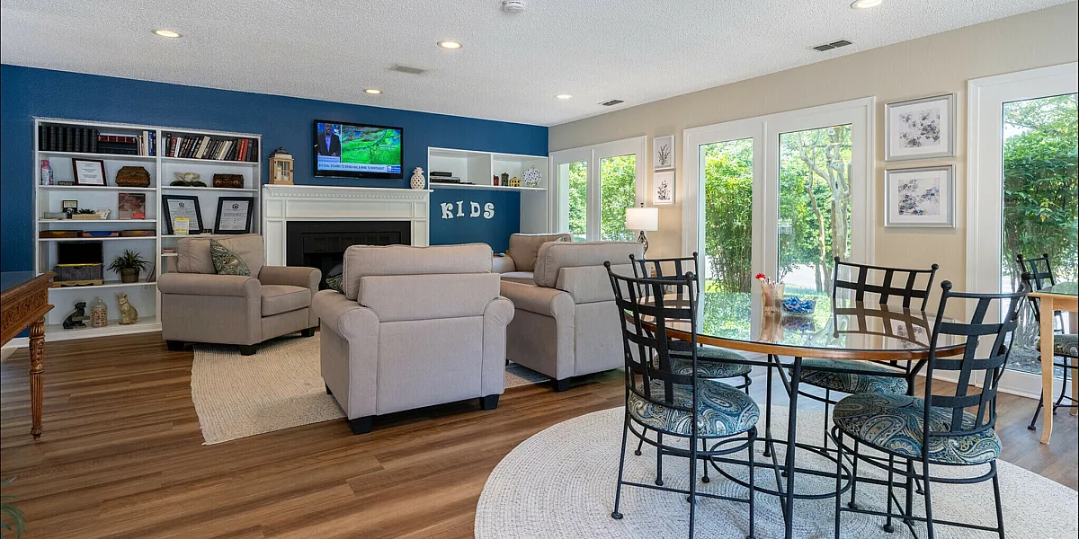 Spacious living room with cozy seating, a flat-screen TV, and a dining area near large windows bringing in natural light.