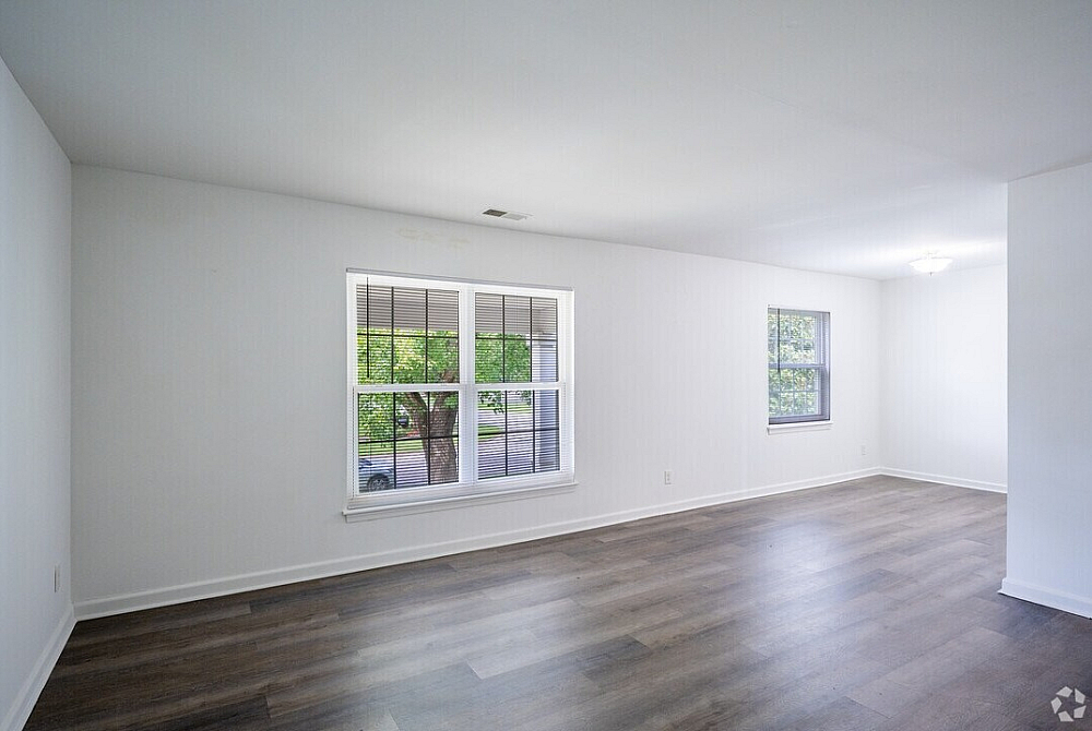 Bright, spacious living area with large windows and elegant hardwood flooring, perfect for a welcoming and open home environment.