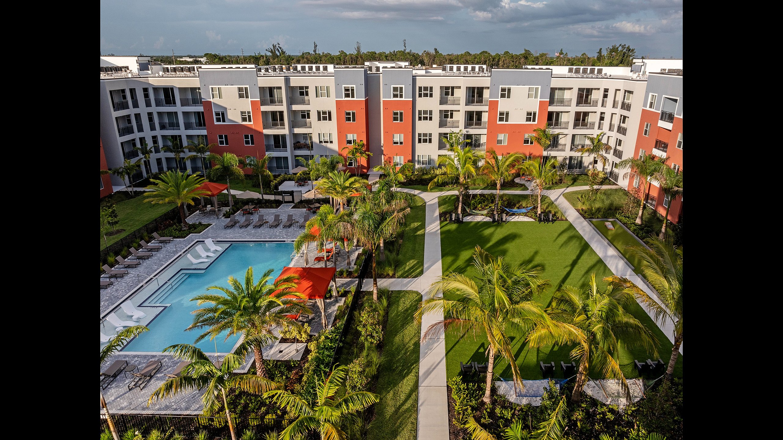 Beautiful apartment complex featuring a pristine swimming pool, lush gardens, and modern architecture.