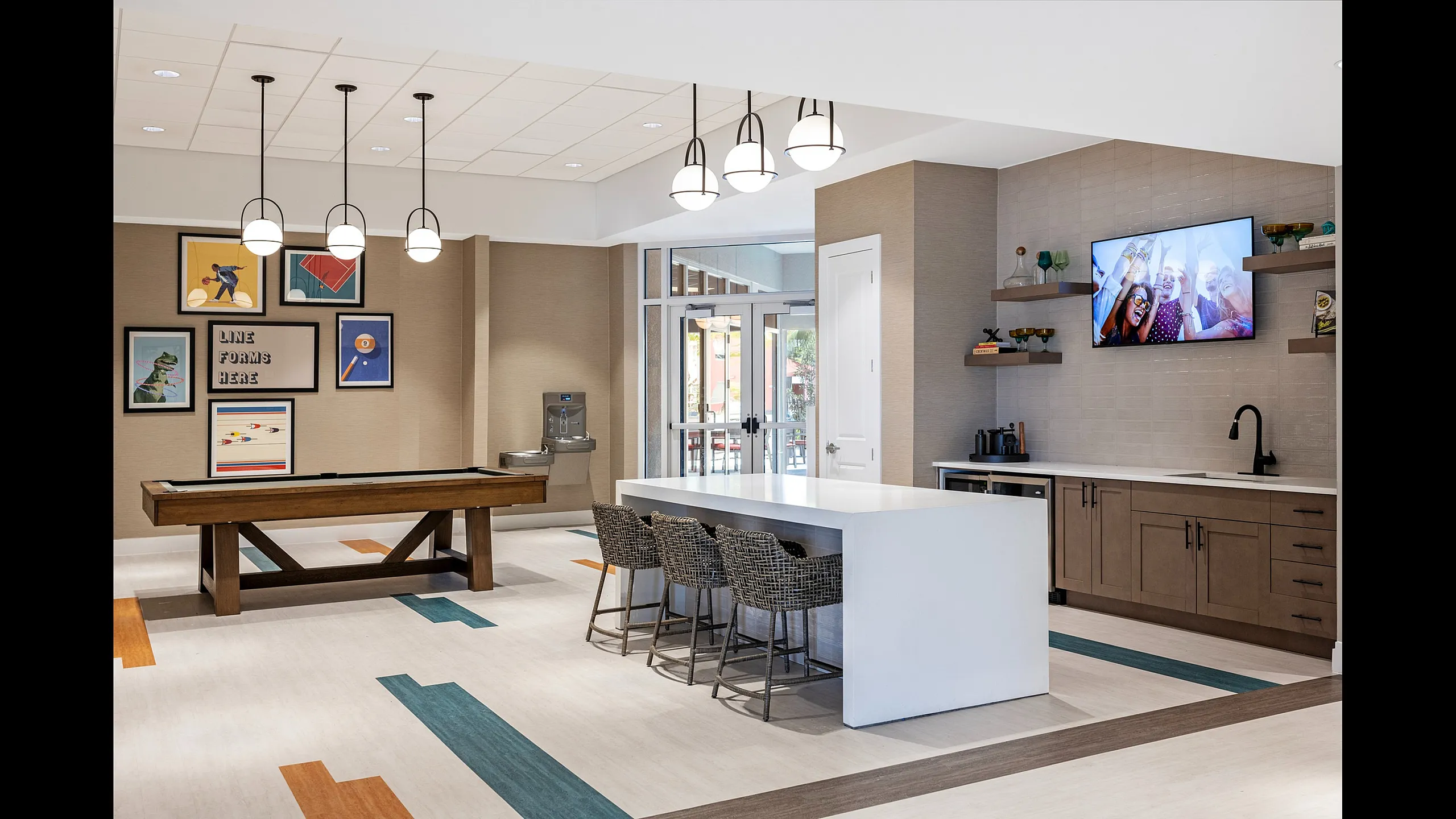 Modern recreation room with stylish pool table, contemporary art, and sleek bar seating.