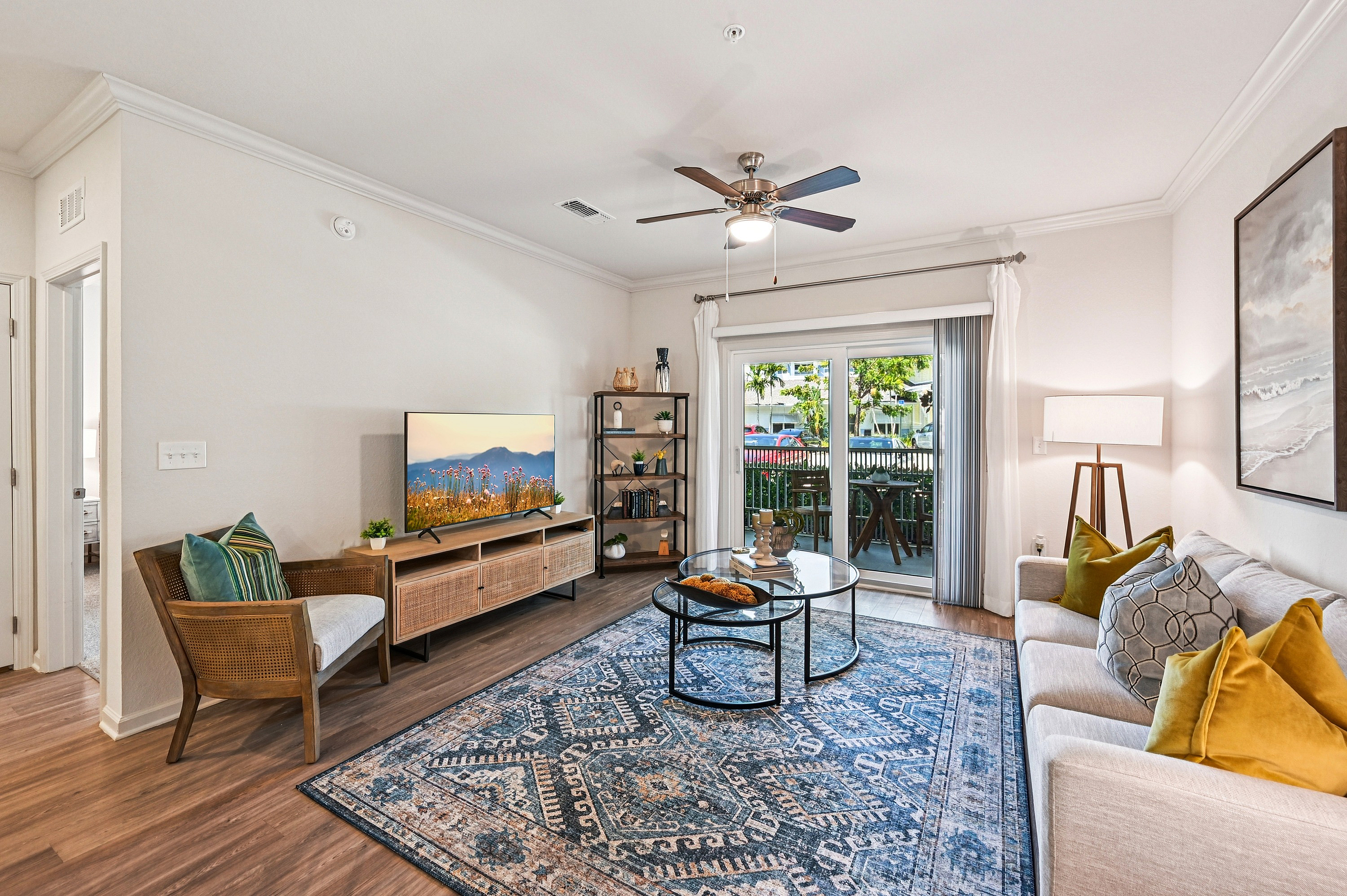 Bright and inviting living room with elegant decor, featuring a spacious sitting area, cozy couch, and stylish accent pieces. Large glass doors open to a serene outdoor patio, perfect for relaxation.