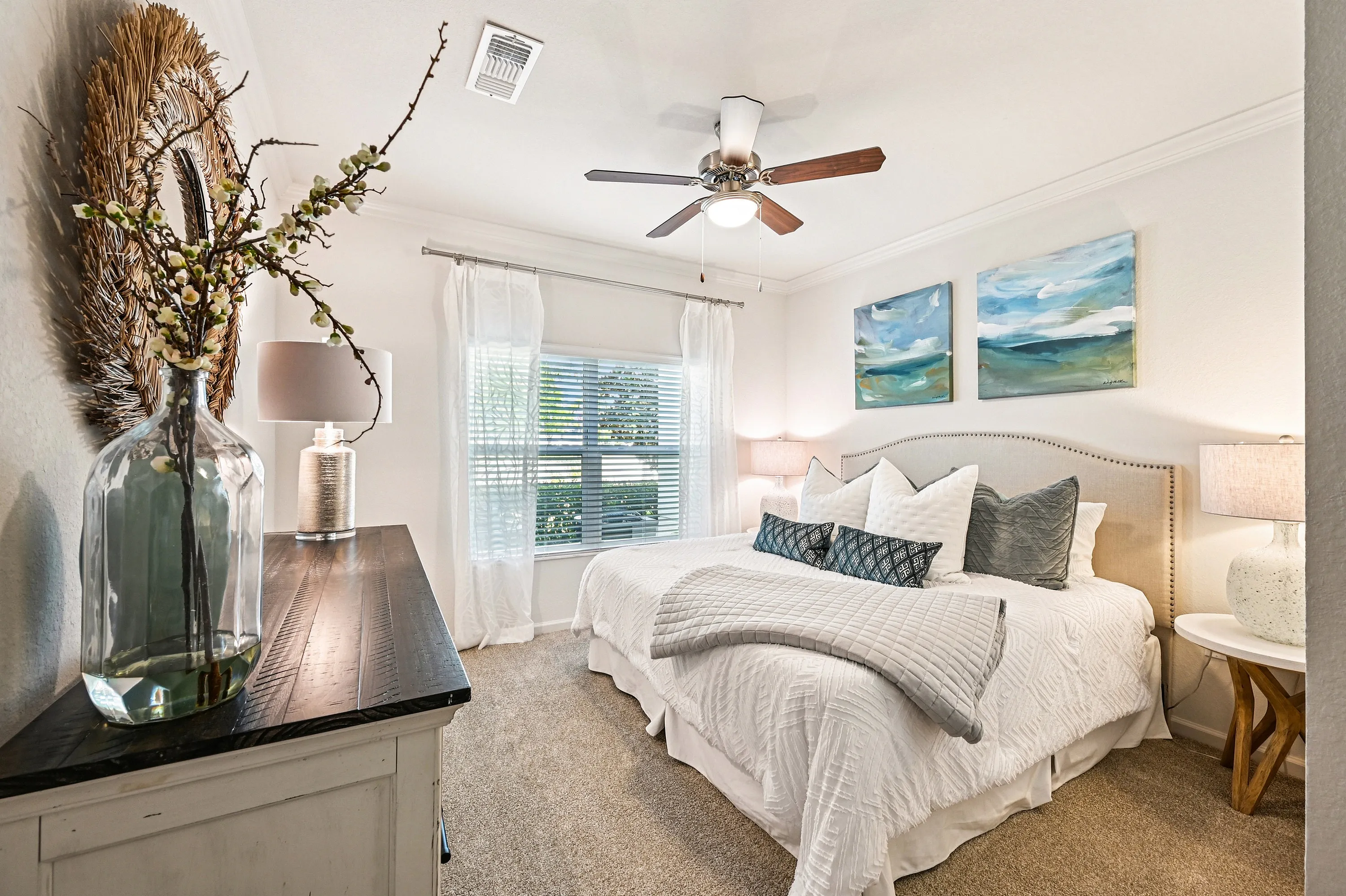 Elegant bedroom featuring a cozy king-sized bed, soft lighting, and tasteful artwork. Natural light flows through large windows, highlighting the serene and stylish decor.