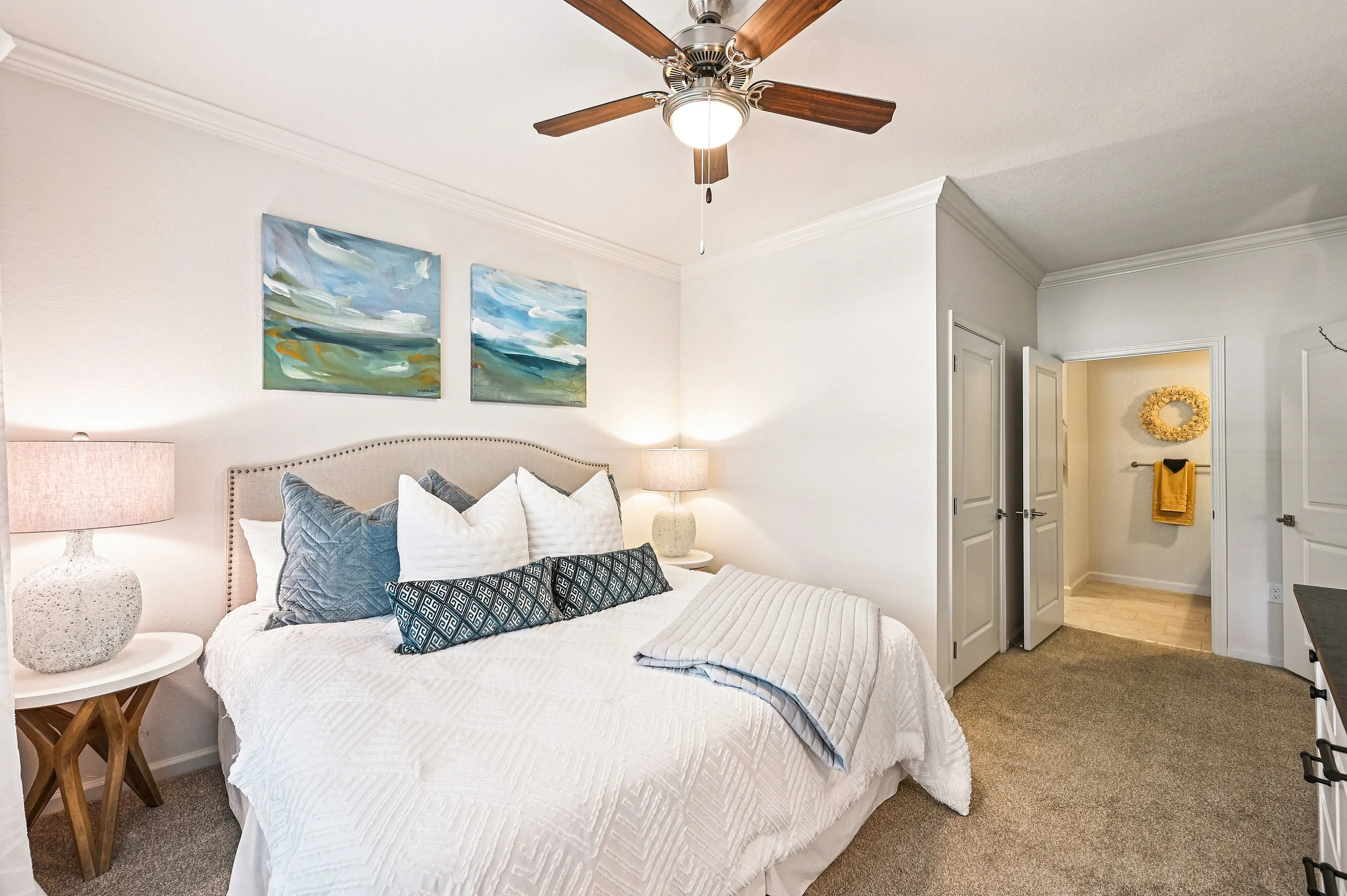 Inviting bedroom with plush bedding, abstract art, and warm lighting creates a cozy and serene atmosphere.