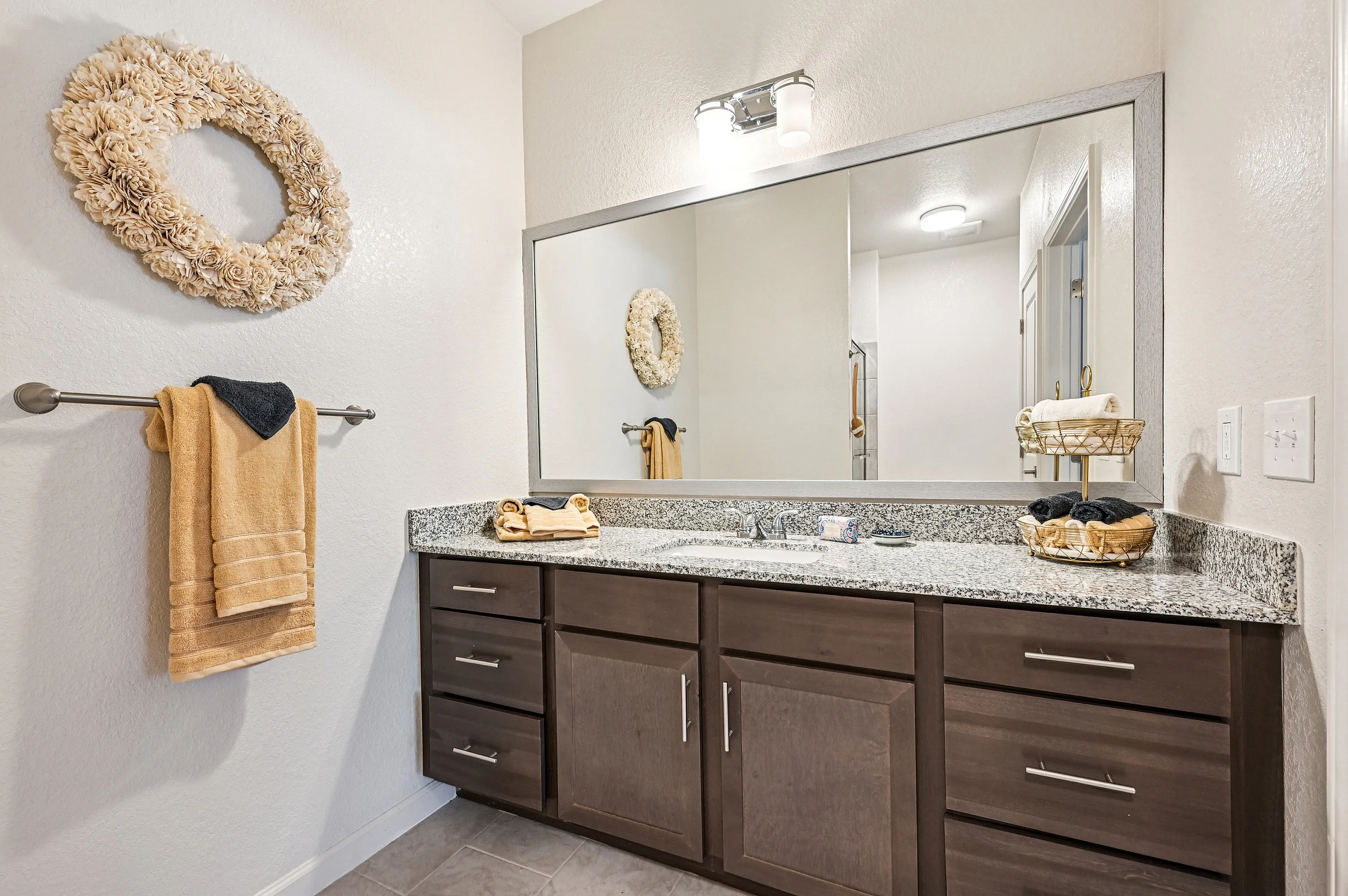 Sleek and modern bathroom with elegant granite countertop, stylish dark wood cabinetry, and luxurious decor.