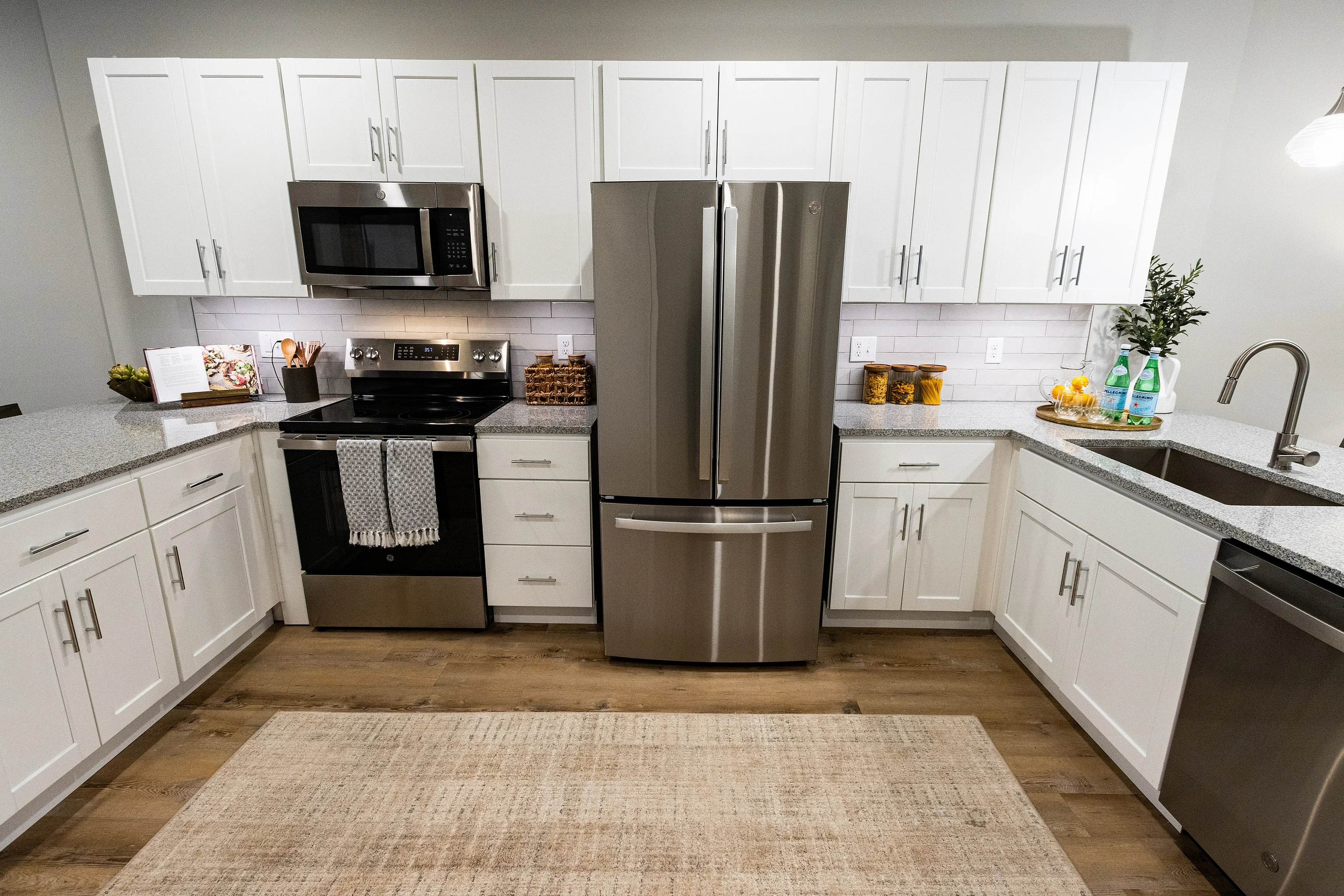 Modern kitchen with sleek stainless steel appliances, white cabinetry, and elegant granite countertops.