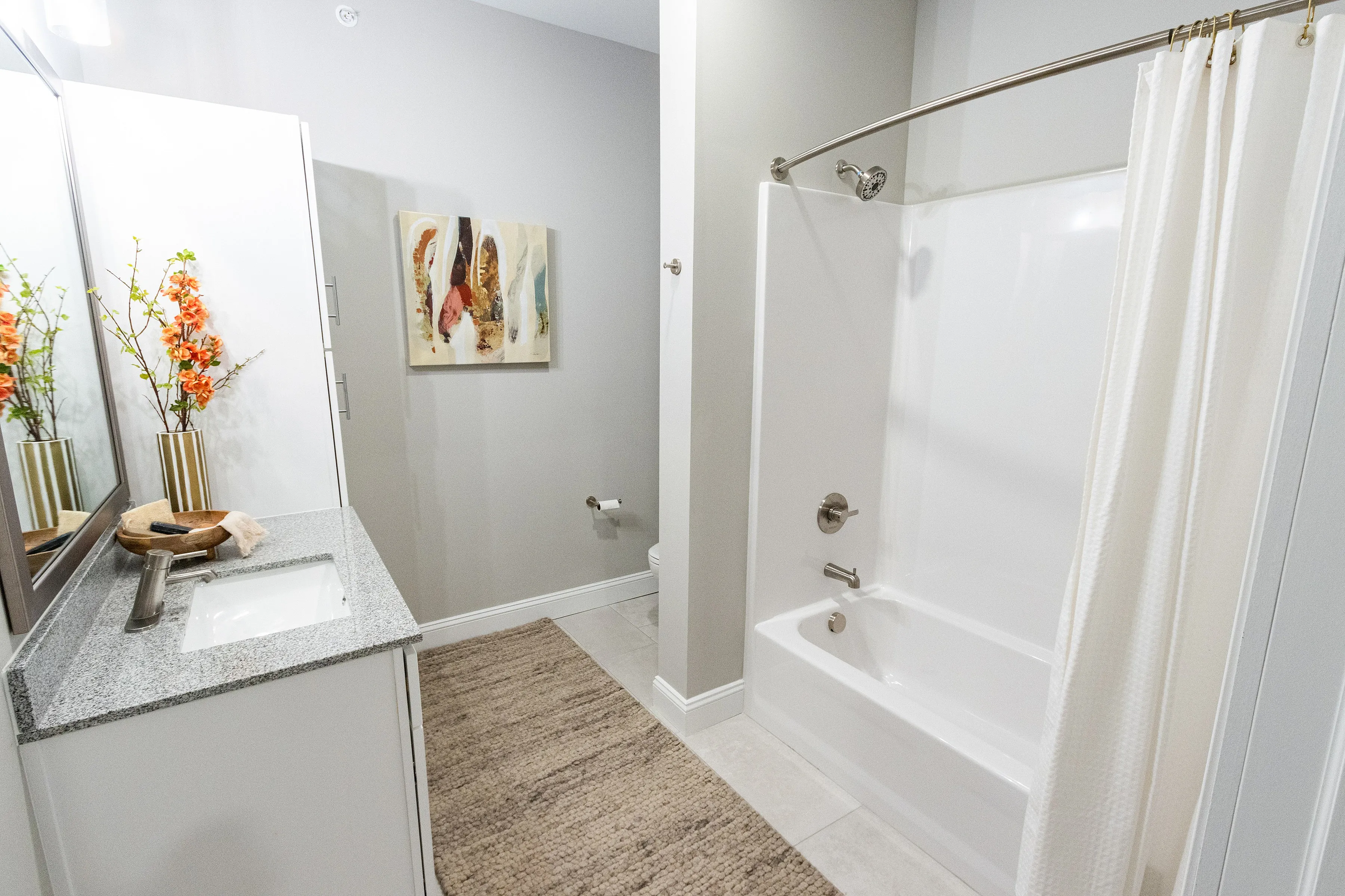 Modern bathroom with sleek granite countertop, elegant floral decor, and a spacious bathtub offering a tranquil retreat.