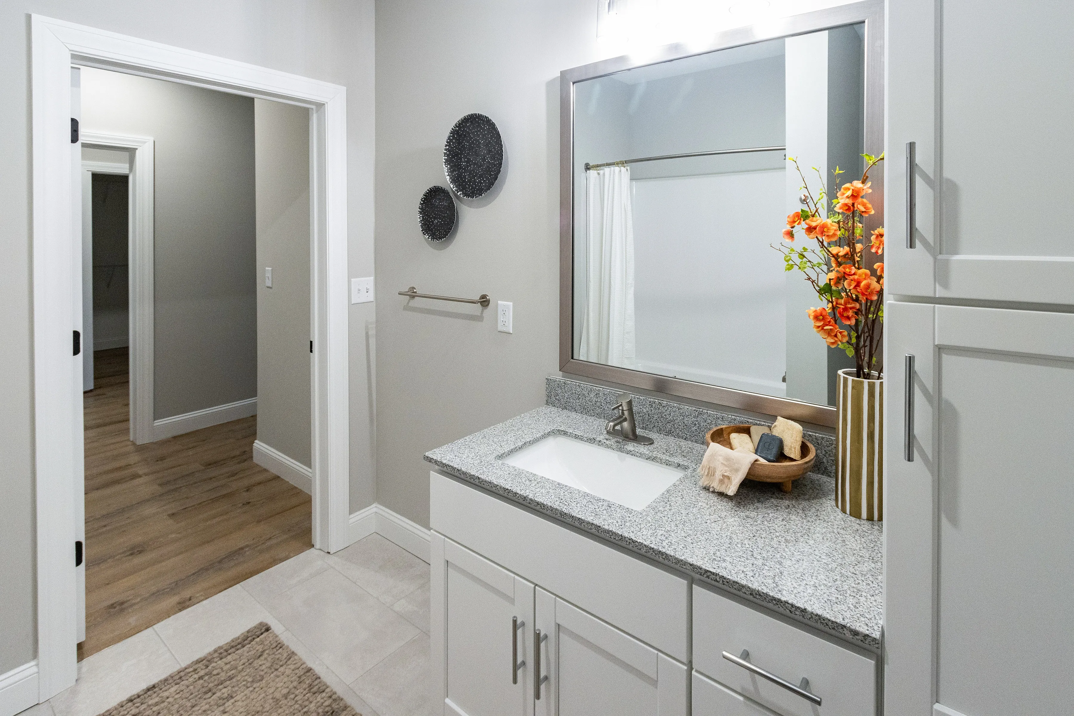 Chic bathroom with stylish vanity, granite countertop, and vibrant orange flowers enhancing the inviting space.