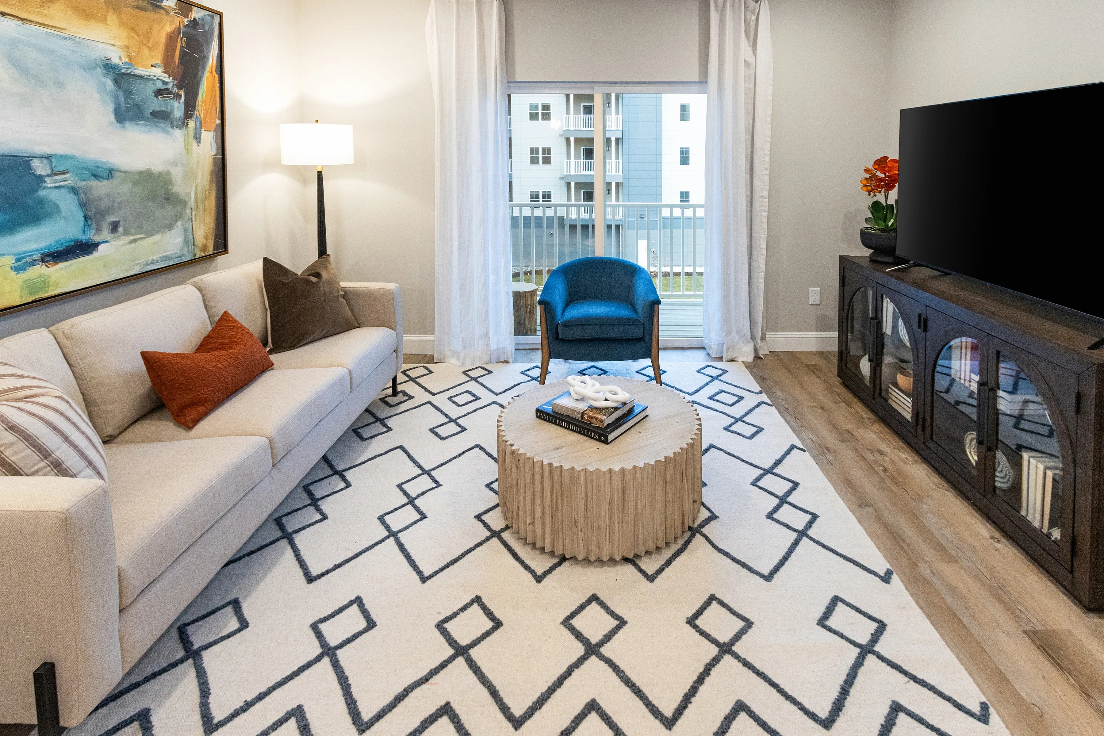 Inviting living room with modern decor, featuring a plush sofa, vibrant artwork, and a stylish coffee table on a chic geometric rug.