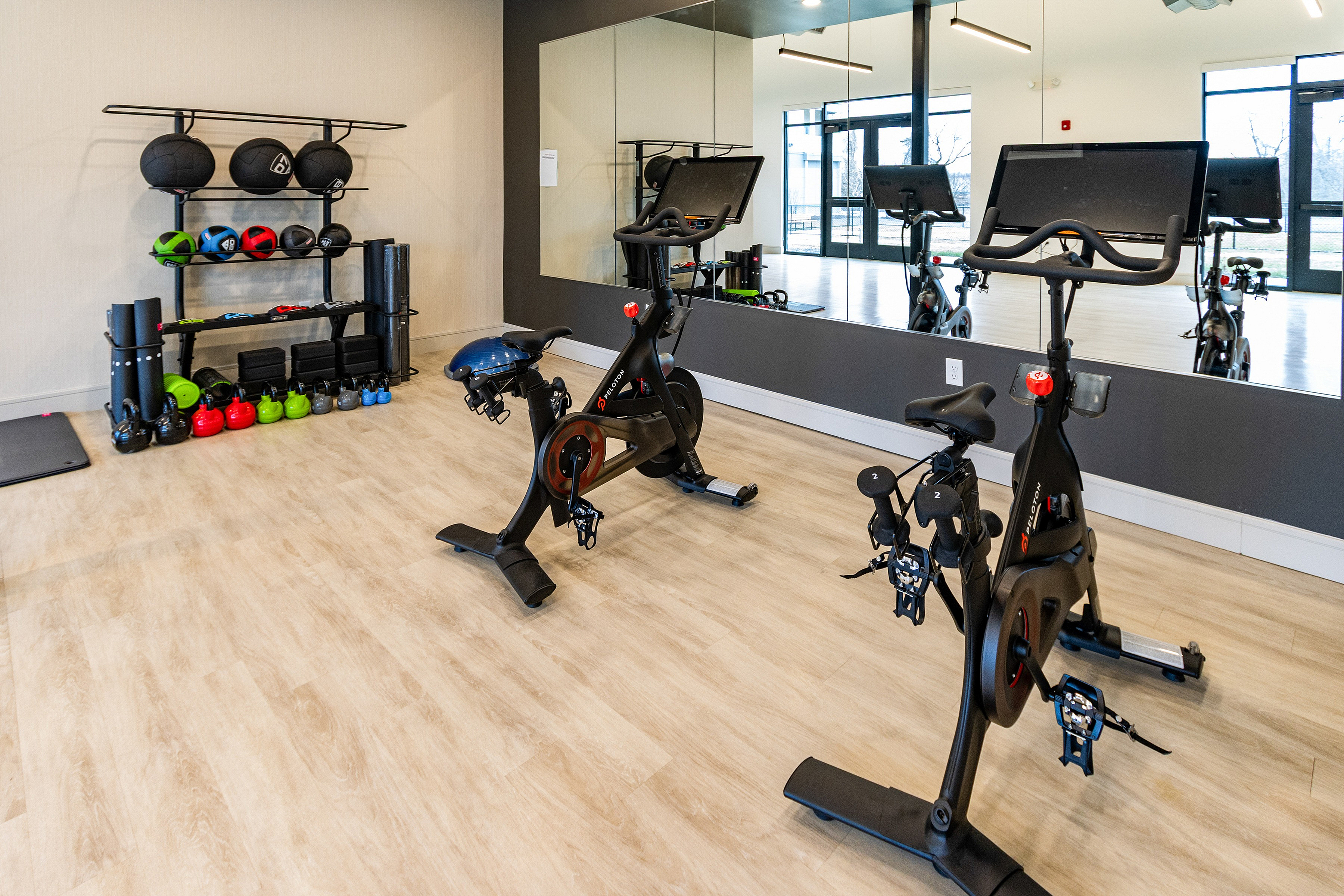 Modern fitness room featuring sleek Peloton bikes, vibrant kettlebells, and comprehensive workout equipment for a complete exercise experience.