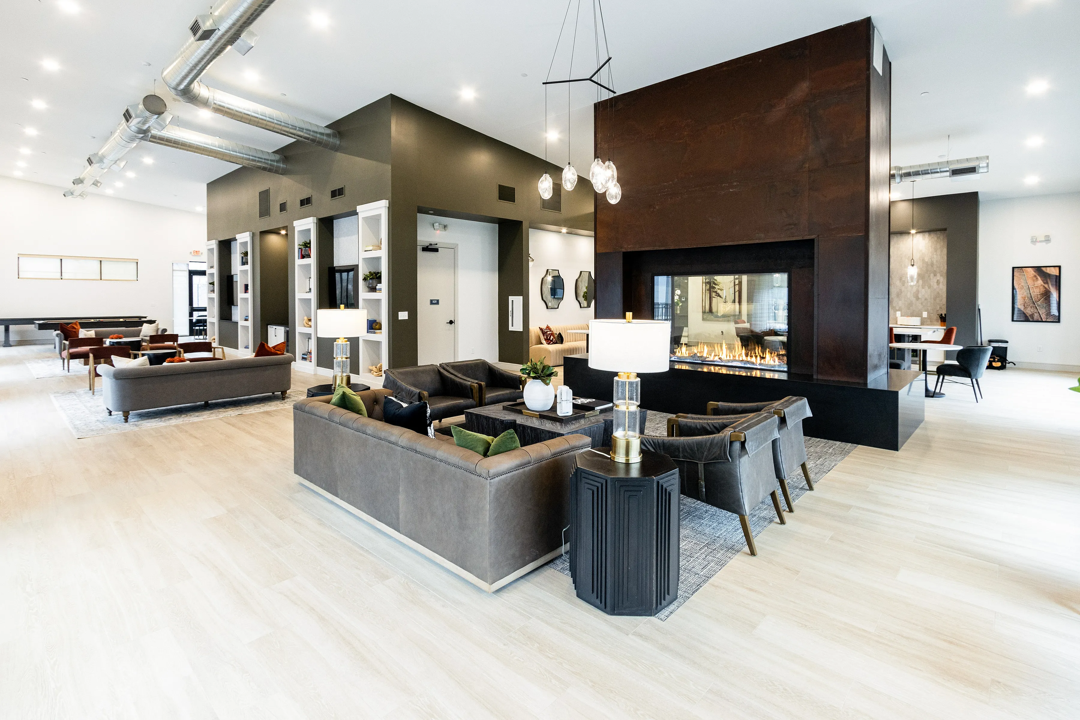Elegant, modern lounge space featuring cozy sofas, a sleek double-sided fireplace, and chic industrial details.