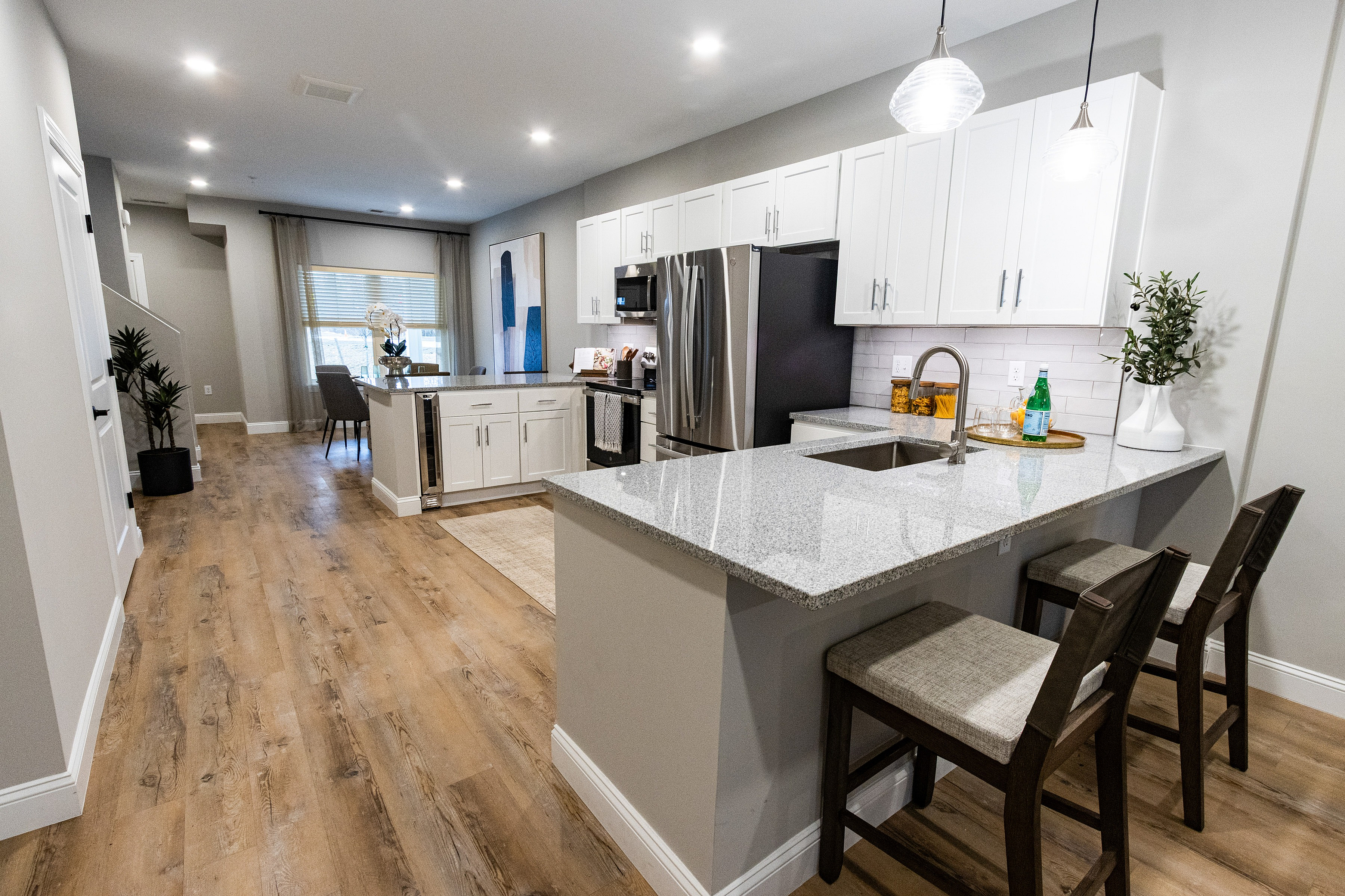 Contemporary open-concept kitchen with sleek granite countertops, stainless steel appliances, and cozy dining area highlighting elegant hardwood flooring.