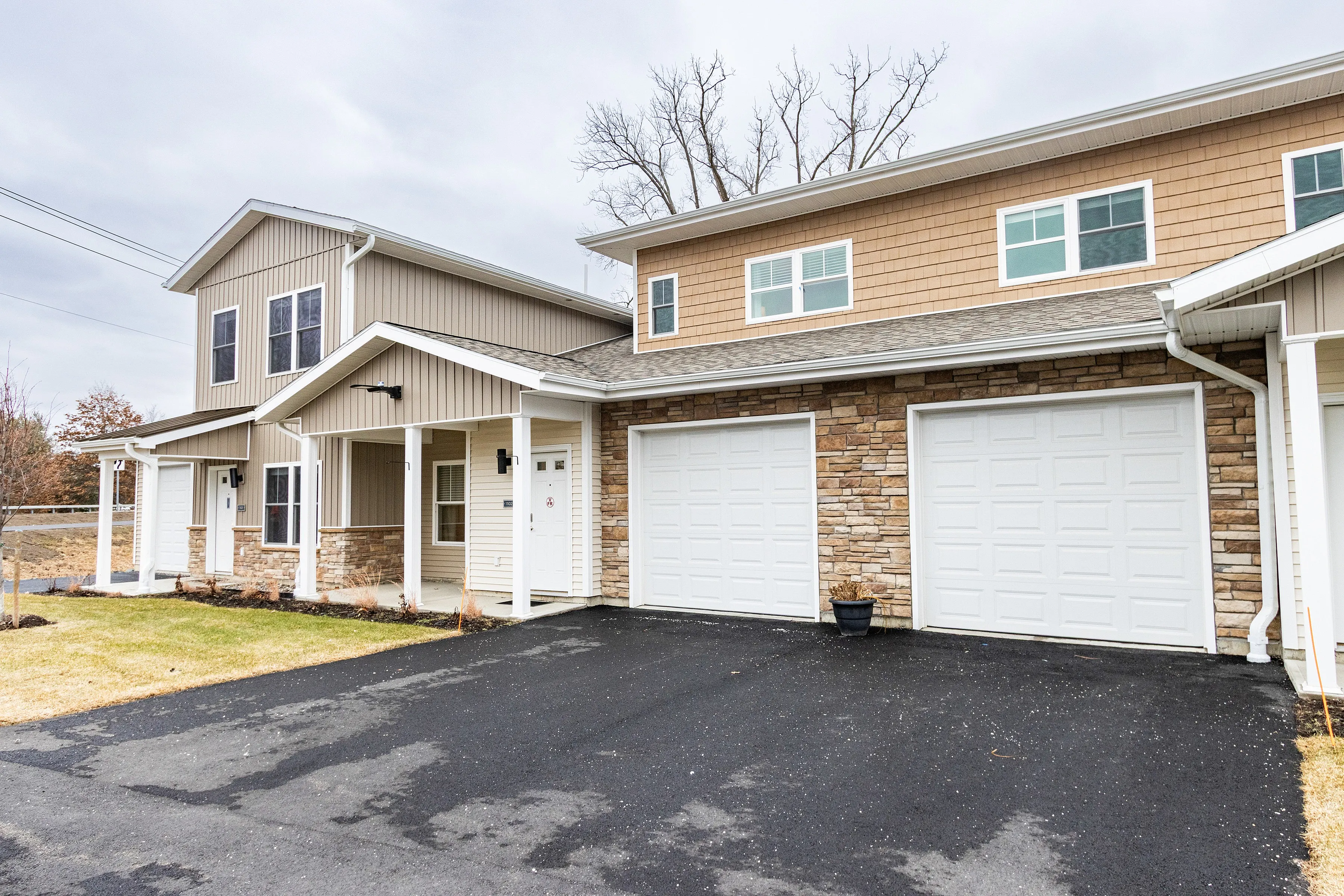 Charming two-story townhouse with dual garages and a stylish stone facade nestled in a serene neighborhood.