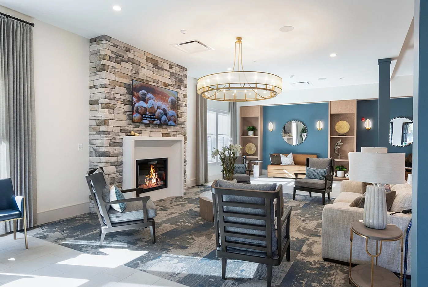 Inviting living room with a cozy fireplace, modern stone accent wall, elegant chandelier, and stylish seating area.