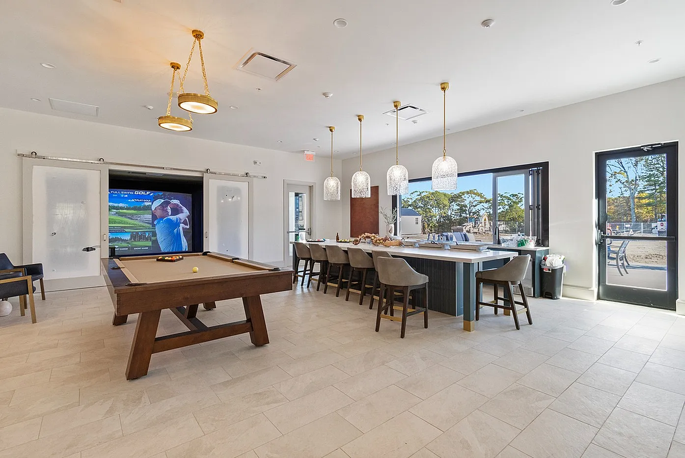 Luxurious clubhouse interior featuring a billiards table and a bar area with elegant pendant lighting, ideal for entertaining.