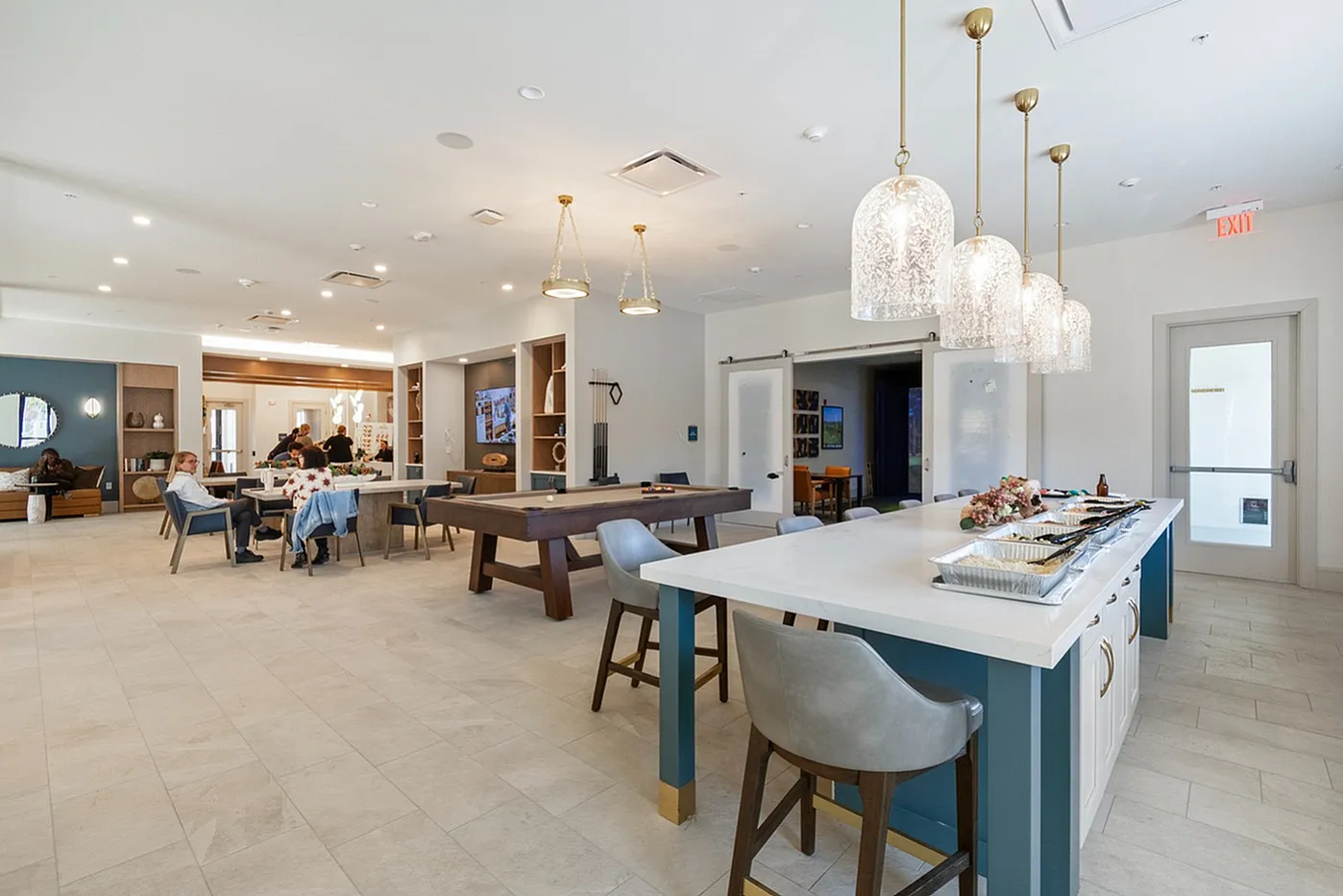 Elegant communal space featuring a modern open layout with a kitchen island, stylish pendant lighting, pool table, and comfortable seating area.