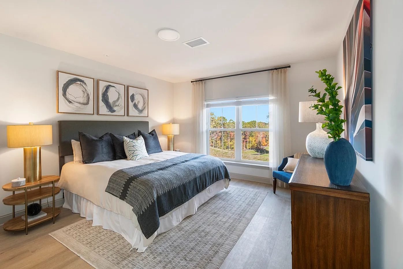 Bright and inviting bedroom with modern decor, featuring a large window overlooking scenic views, cozy bedding, and stylish artwork.