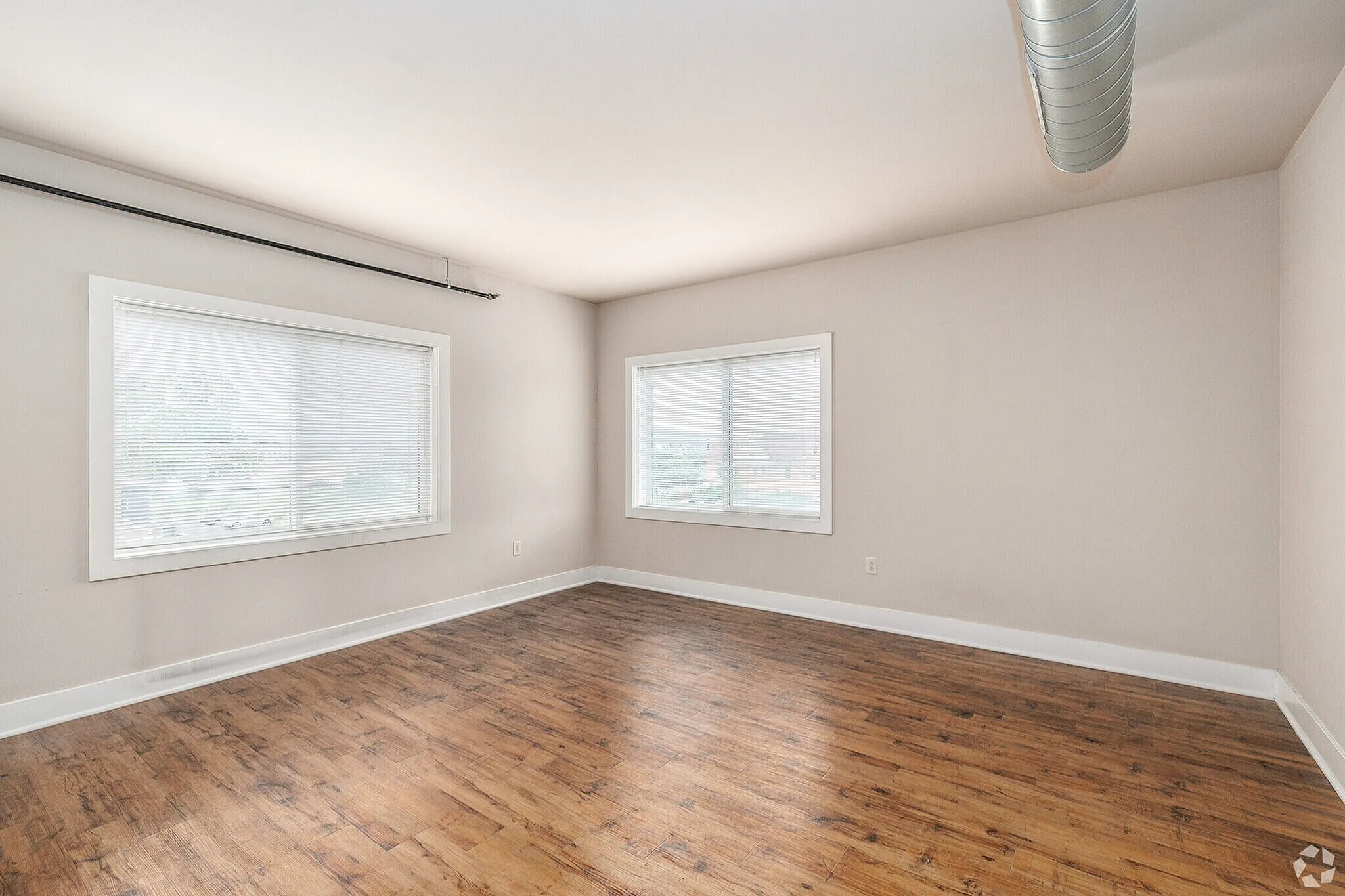 Bright and spacious room with large windows and elegant wood flooring, perfect for customizable living space.