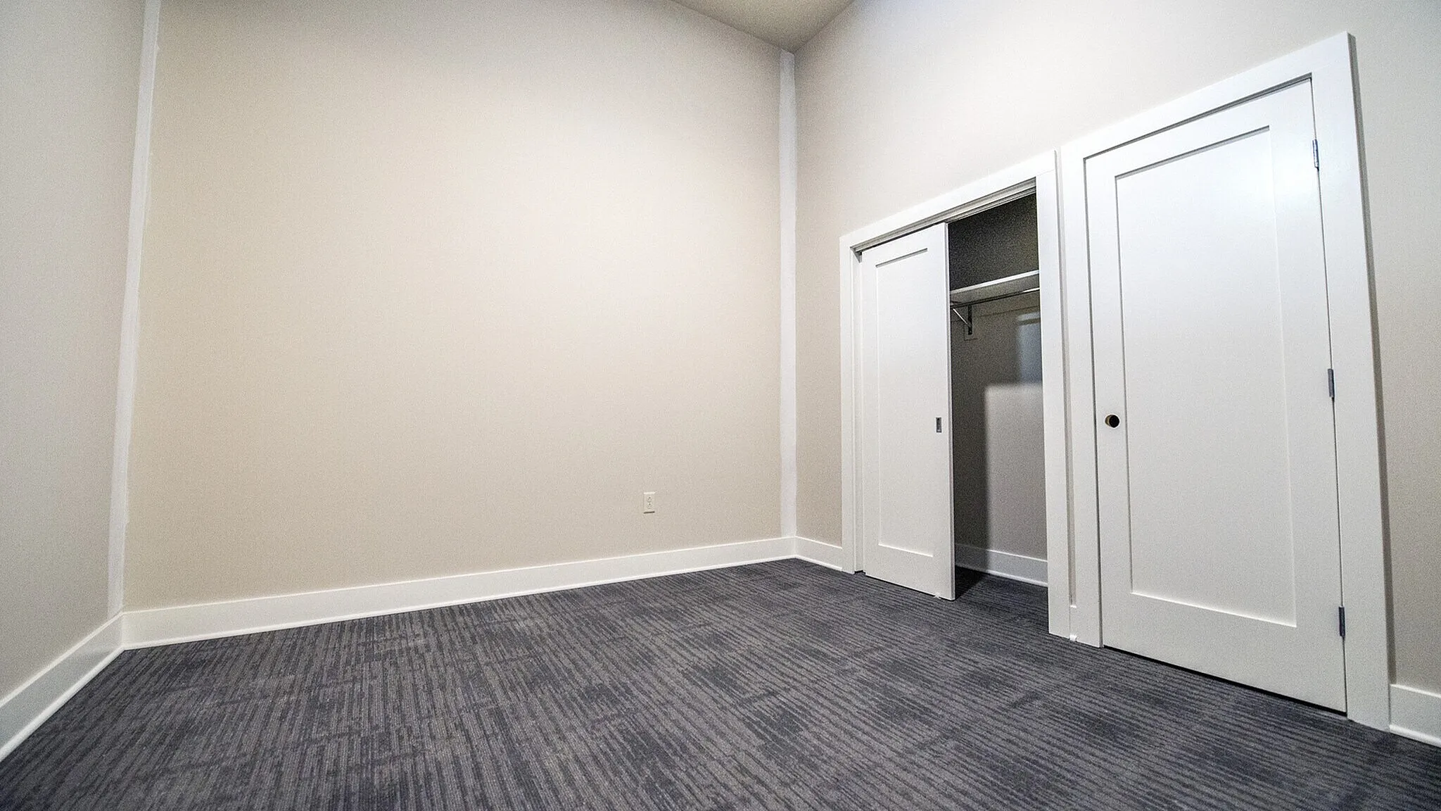 Contemporary room with plush carpet and built-in closet, offering modern elegance and ample space for personalization.