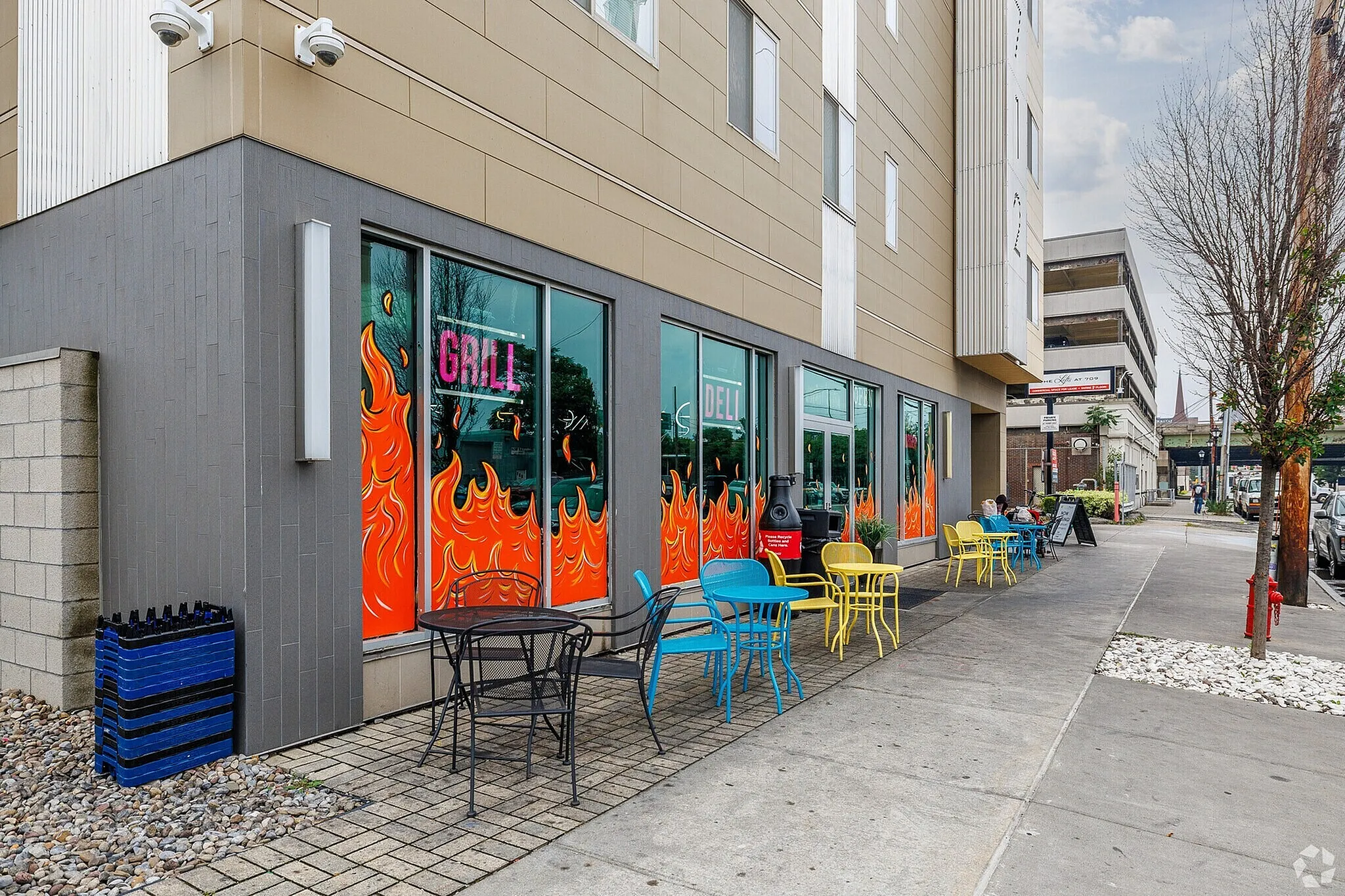 Vibrant urban cafe with colorful outdoor seating and eye-catching flame-themed window art.
