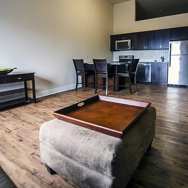 Modern open-plan kitchen and living area with sleek appliances, chic dining space, and warm wooden flooring.