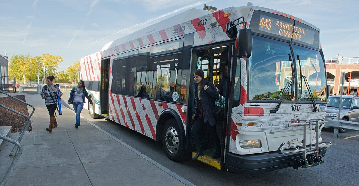 Vibrant city bus with colorful design picking up passengers at a busy urban stop.