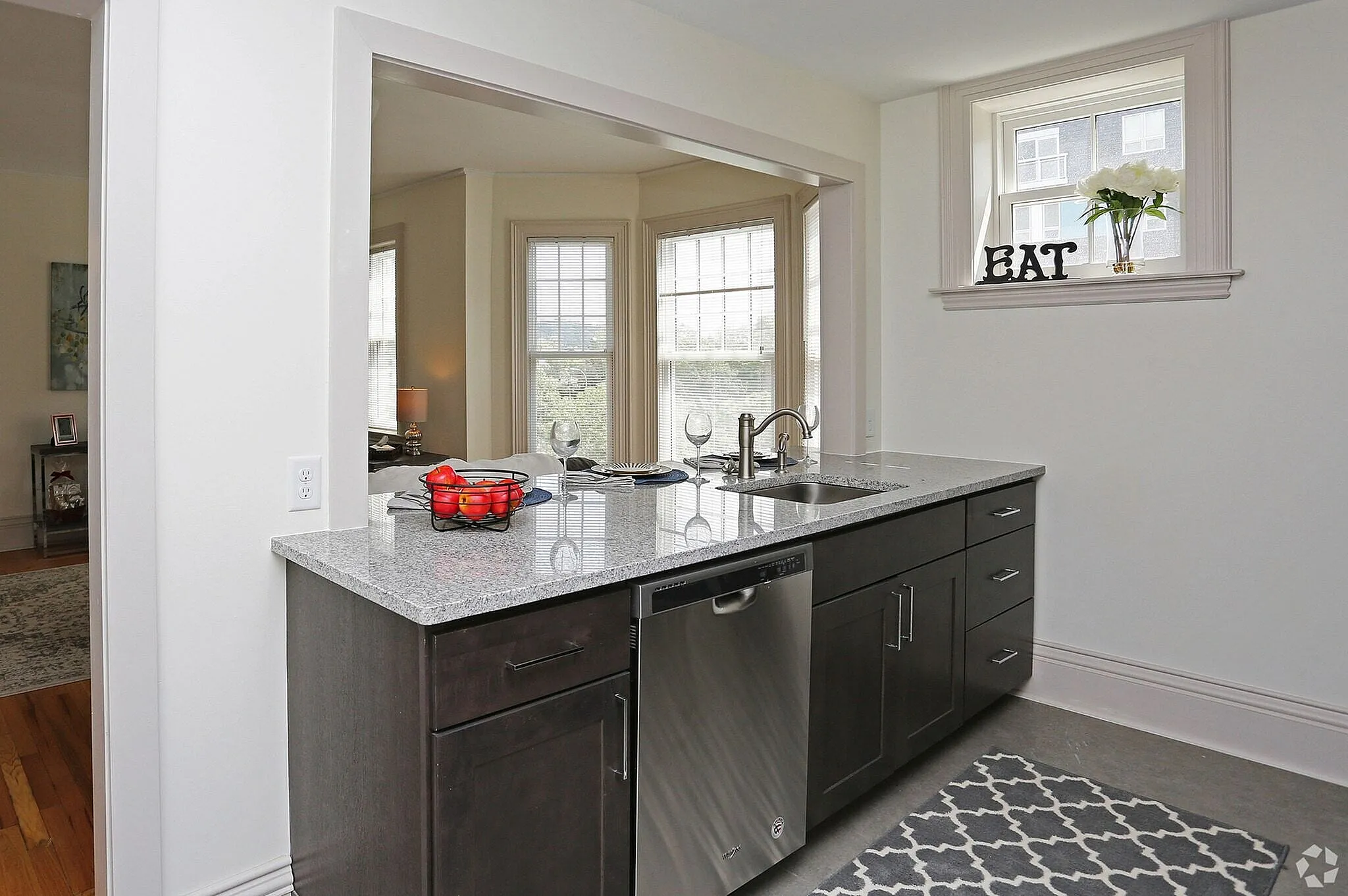 Bright, modern kitchen with a granite countertop, stainless steel appliances, and a cozy view of the living area.