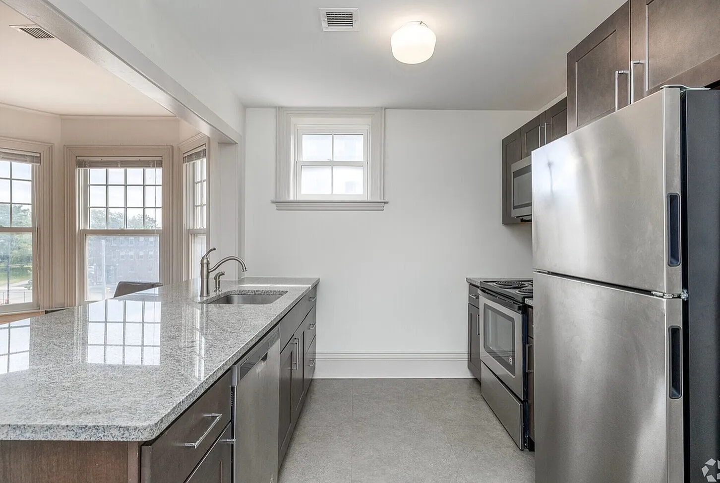 Modern kitchen with sleek stainless steel appliances, elegant granite countertops, and large windows providing abundant natural light.