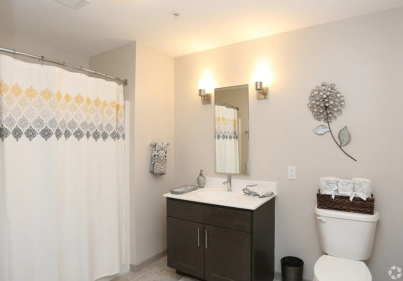 Elegant bathroom featuring a modern vanity, stylish floral wall art, and a chic patterned shower curtain.