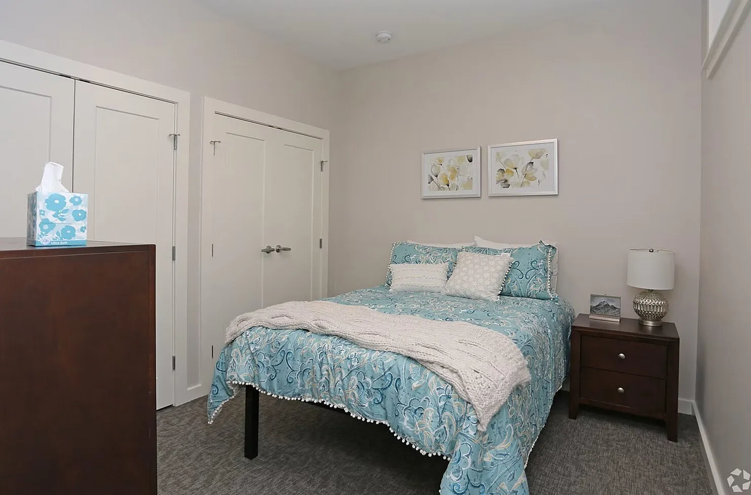 Inviting modern bedroom featuring a cozy bed with stylish blue bedding, elegant artwork, and ample closet space in a serene setting.