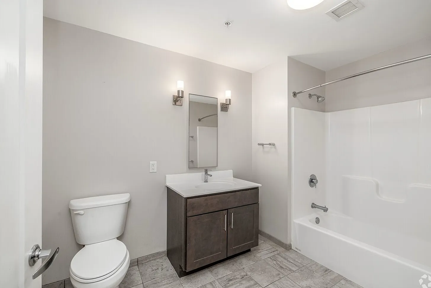 Modern bathroom with elegant lighting, sleek vanity, and a pristine bathtub, boasting clean design and functionality.