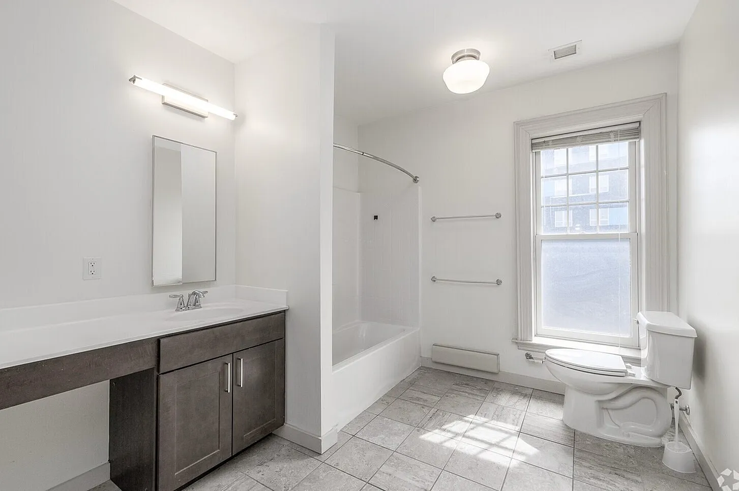 Bright and modern bathroom with elegant tiling, sleek vanity, and a large sunlit window.
