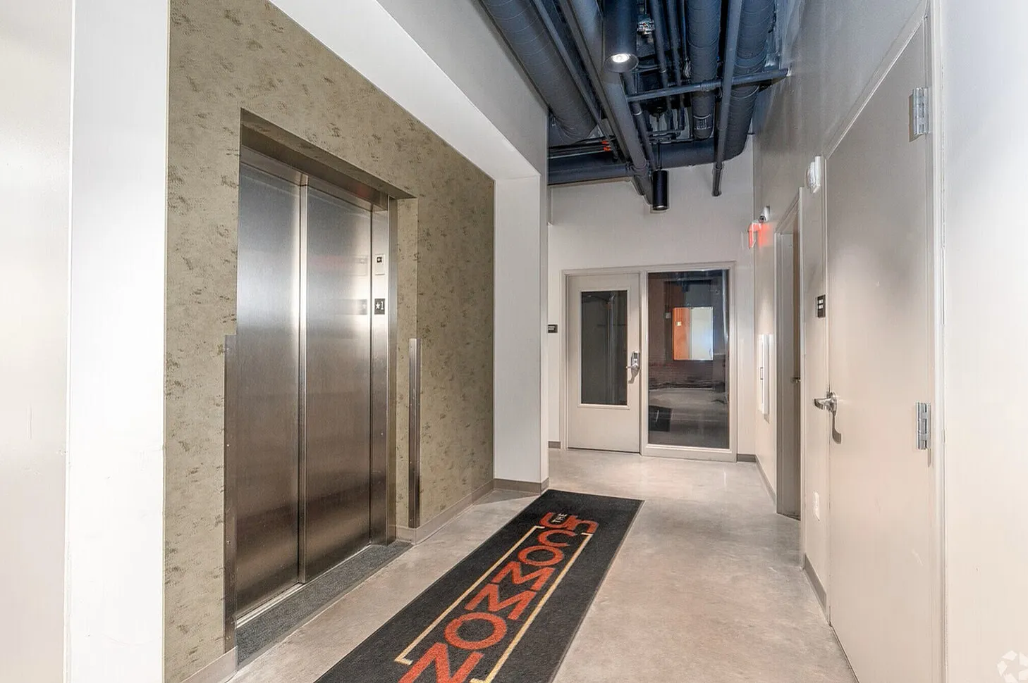 Modern apartment building lobby with sleek elevator and stylish industrial design elements.