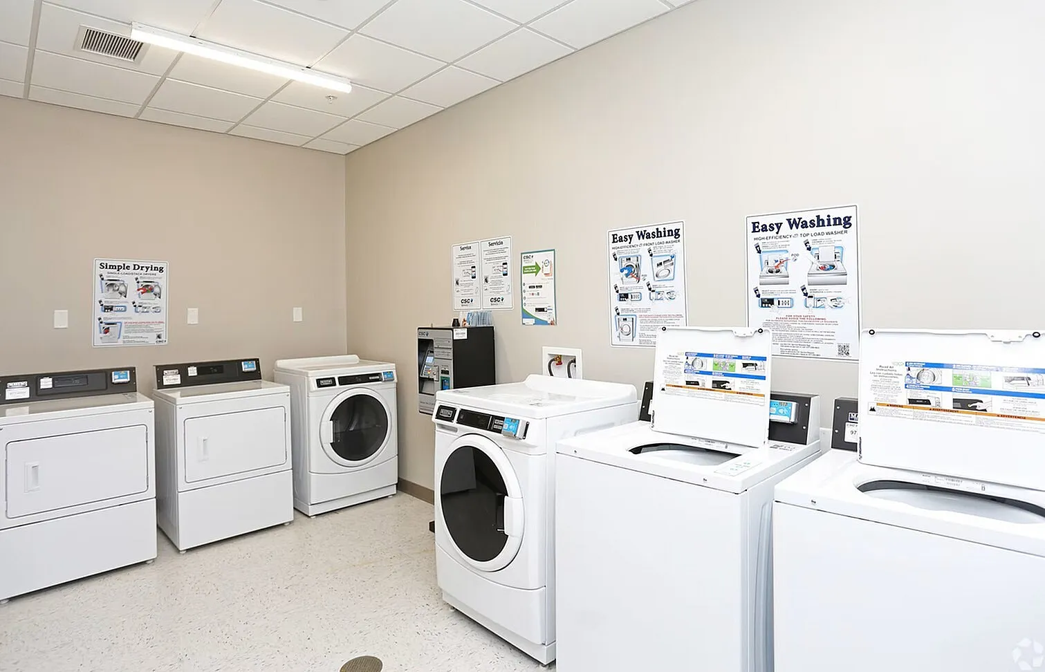 Bright and spacious laundry room equipped with modern washers and dryers, featuring user-friendly instructional signage.