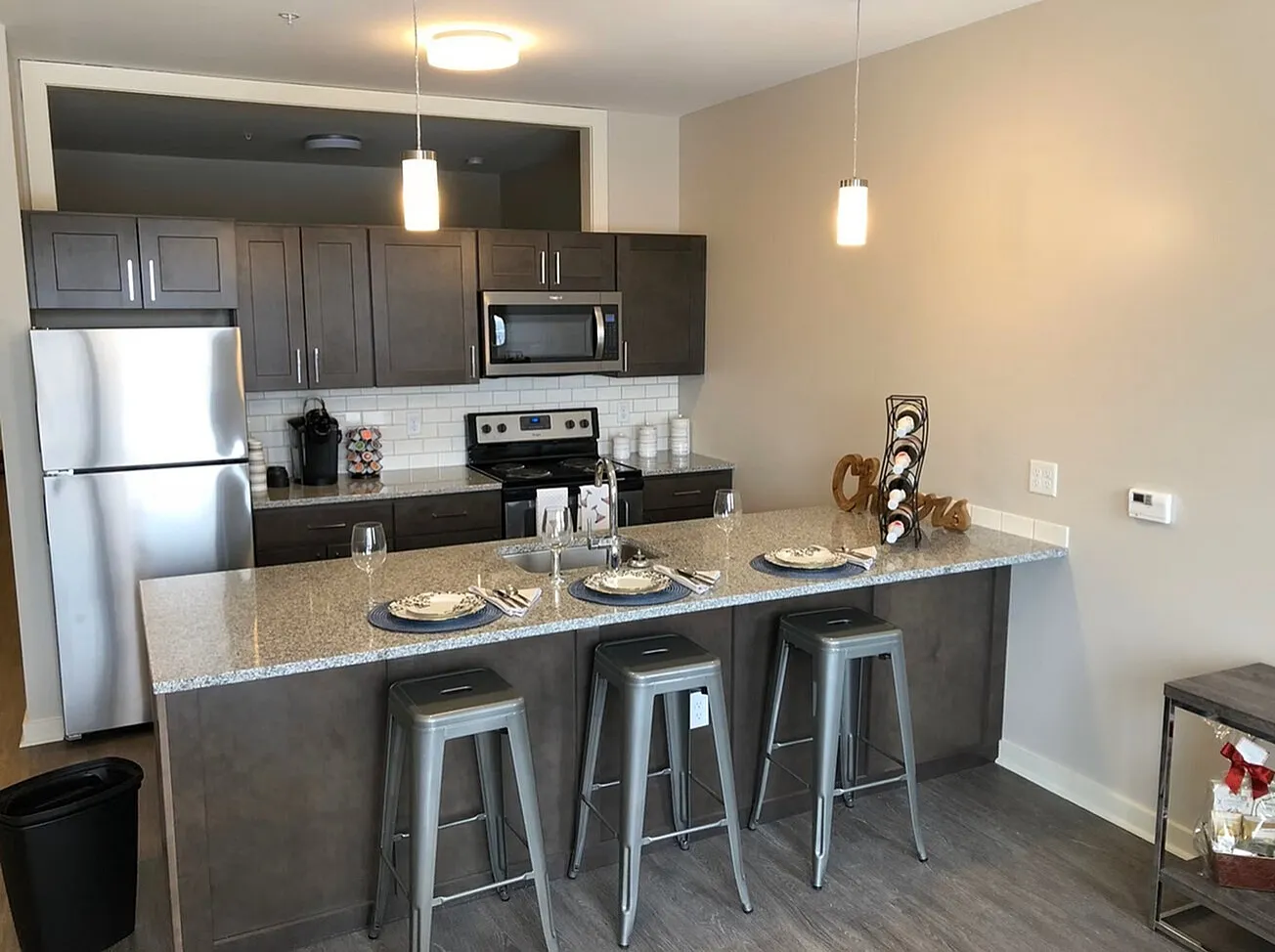 Modern kitchen with sleek stainless steel appliances, elegant dark cabinetry, and a chic breakfast bar with stylish stools.