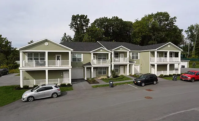 Charming townhouse complex with elegant balconies, nestled in lush greenery, offering cozy and modern living spaces.