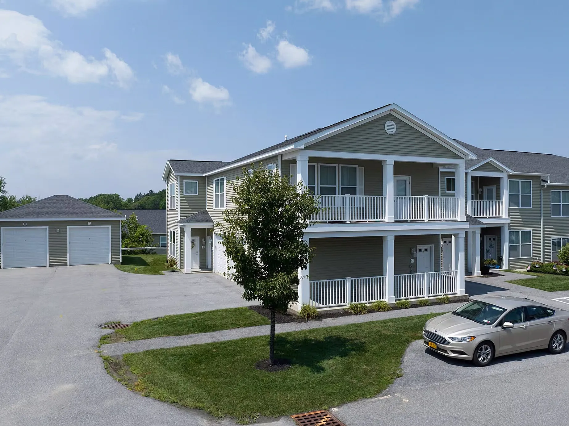 Charming two-story apartment building with inviting balconies, individual garages, and lush greenery, ideal for modern living.