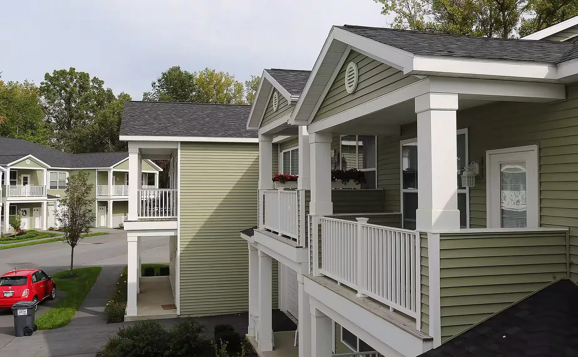 Charming two-story apartments with green siding and inviting balconies, nestled in a serene residential neighborhood.