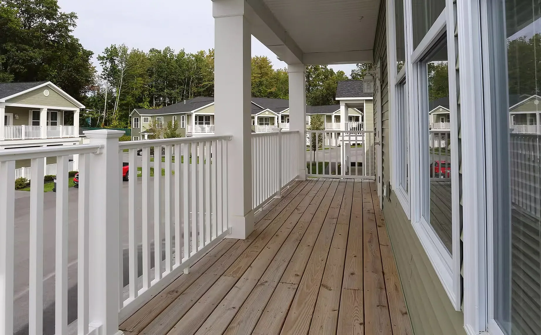 Charming apartment balcony with white railings and a view of lush greenery and neighboring homes, perfect for relaxing.