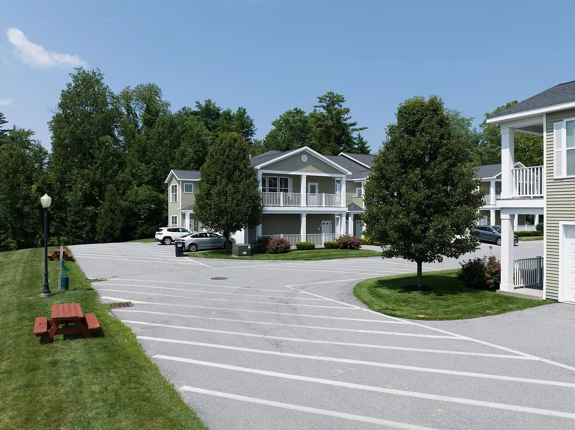 Inviting suburban apartment complex with charming balconies, lush greenery, and ample parking, perfect for serene living.