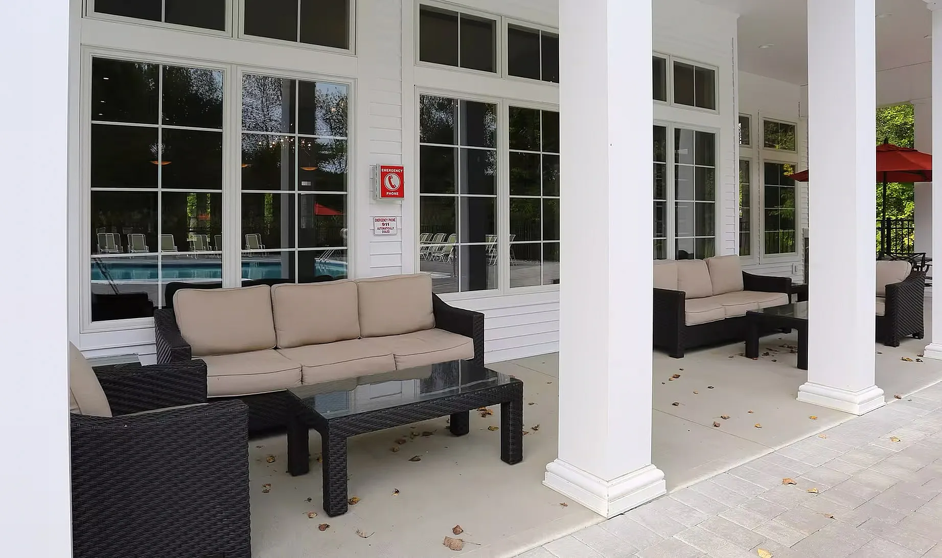 Patio area by the Kensington private pool with overhead coverage, couches, and tables.