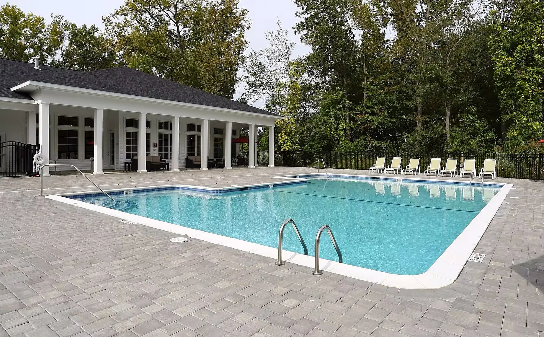 Inviting outdoor pool area surrounded by elegant sun loungers and lush greenery, perfect for relaxation and leisure.