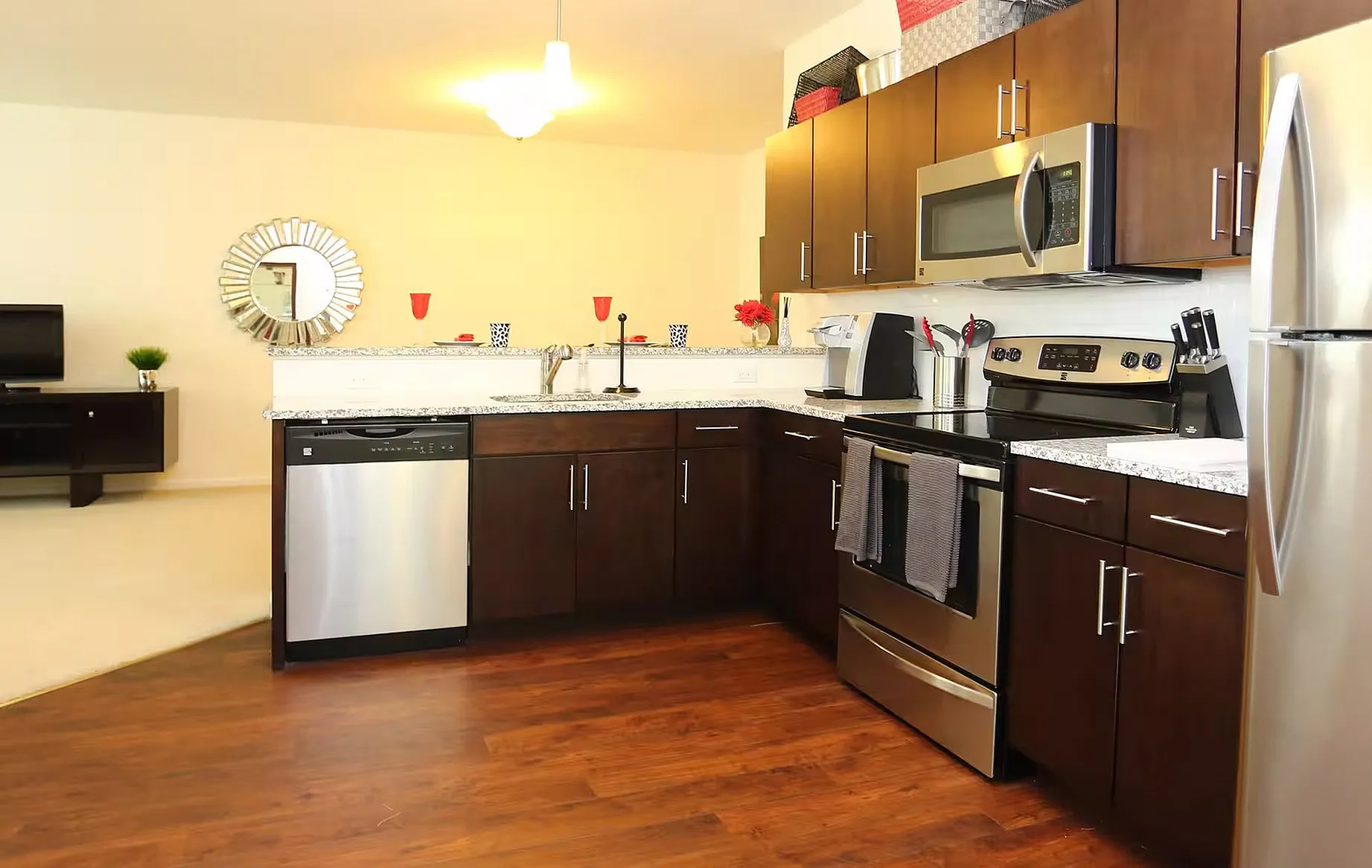 Modern kitchen with sleek stainless steel appliances, elegant dark wood cabinetry, and chic granite countertops, featuring a stylish open layout with hardwood floors.