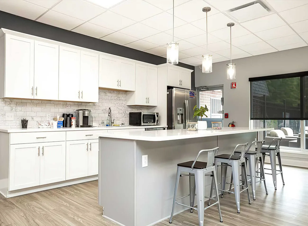 Modern kitchen design with sleek white cabinets, stainless steel appliances, and a trendy breakfast bar with stylish seating.