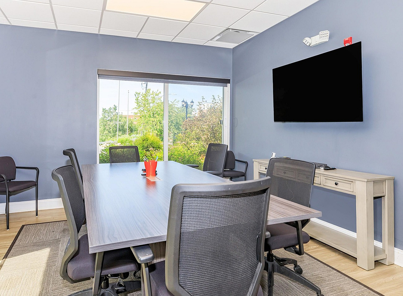 Modern meeting room with sleek conference table, comfortable chairs, and a large window offering a scenic view.