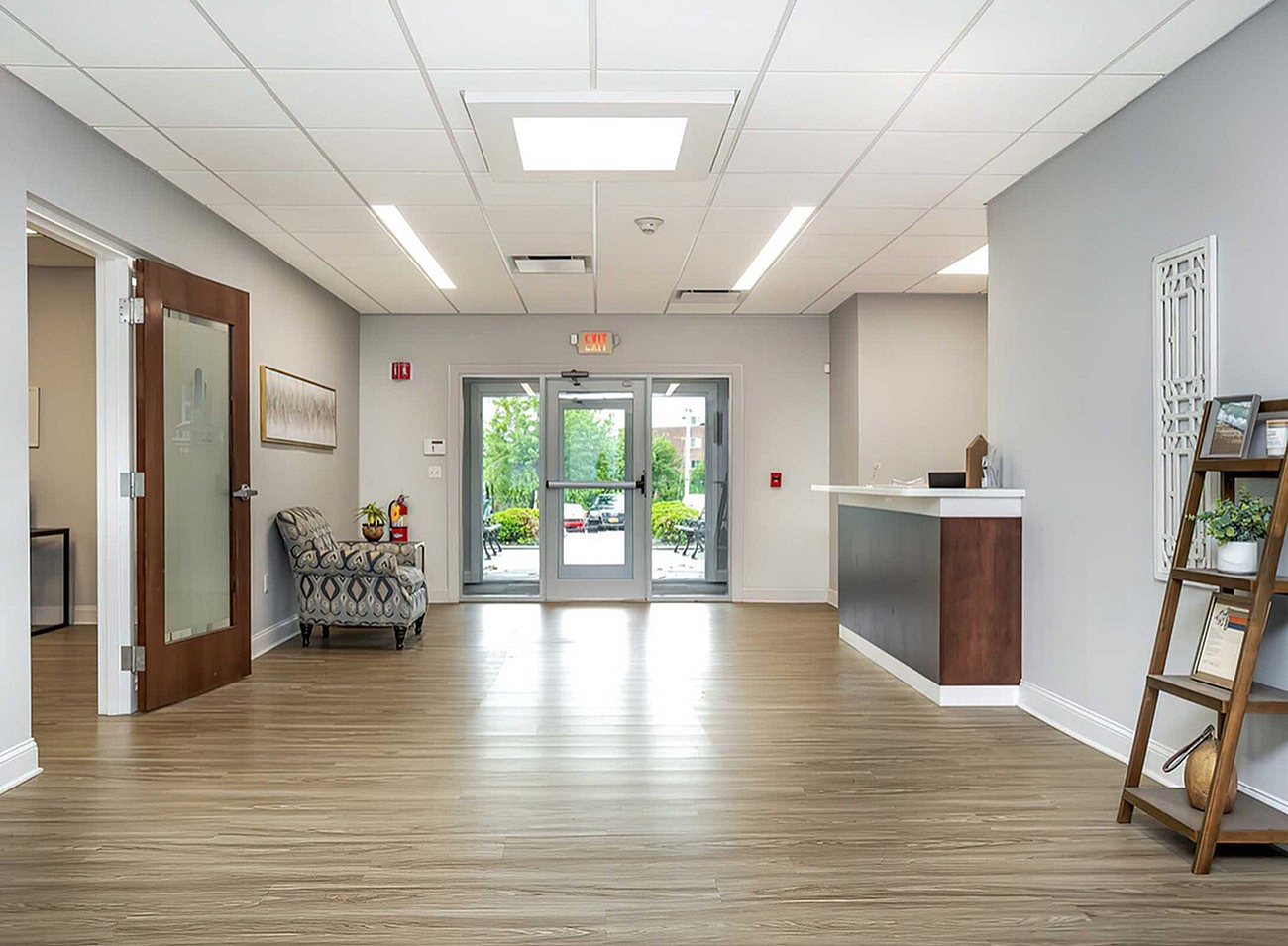 Inviting apartment lobby featuring modern design, sleek wooden flooring, and ambient natural lighting from large windows.
