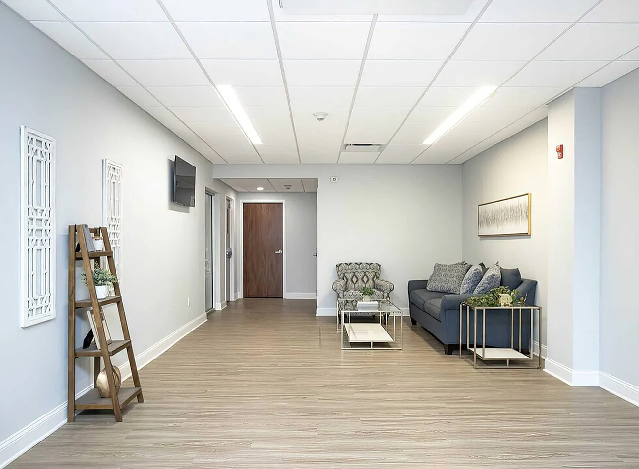 Modern and inviting living room with chic decor, featuring a cozy sofa, elegant armchair, and sleek glass coffee table on beautiful hardwood flooring.