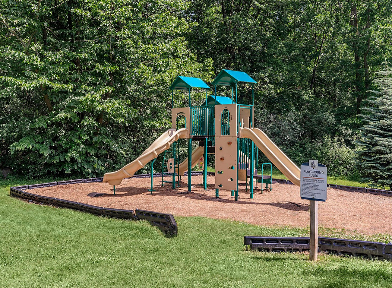 Charming playground featuring vibrant green structures with slides, set amidst lush greenery, offering a perfect family retreat.