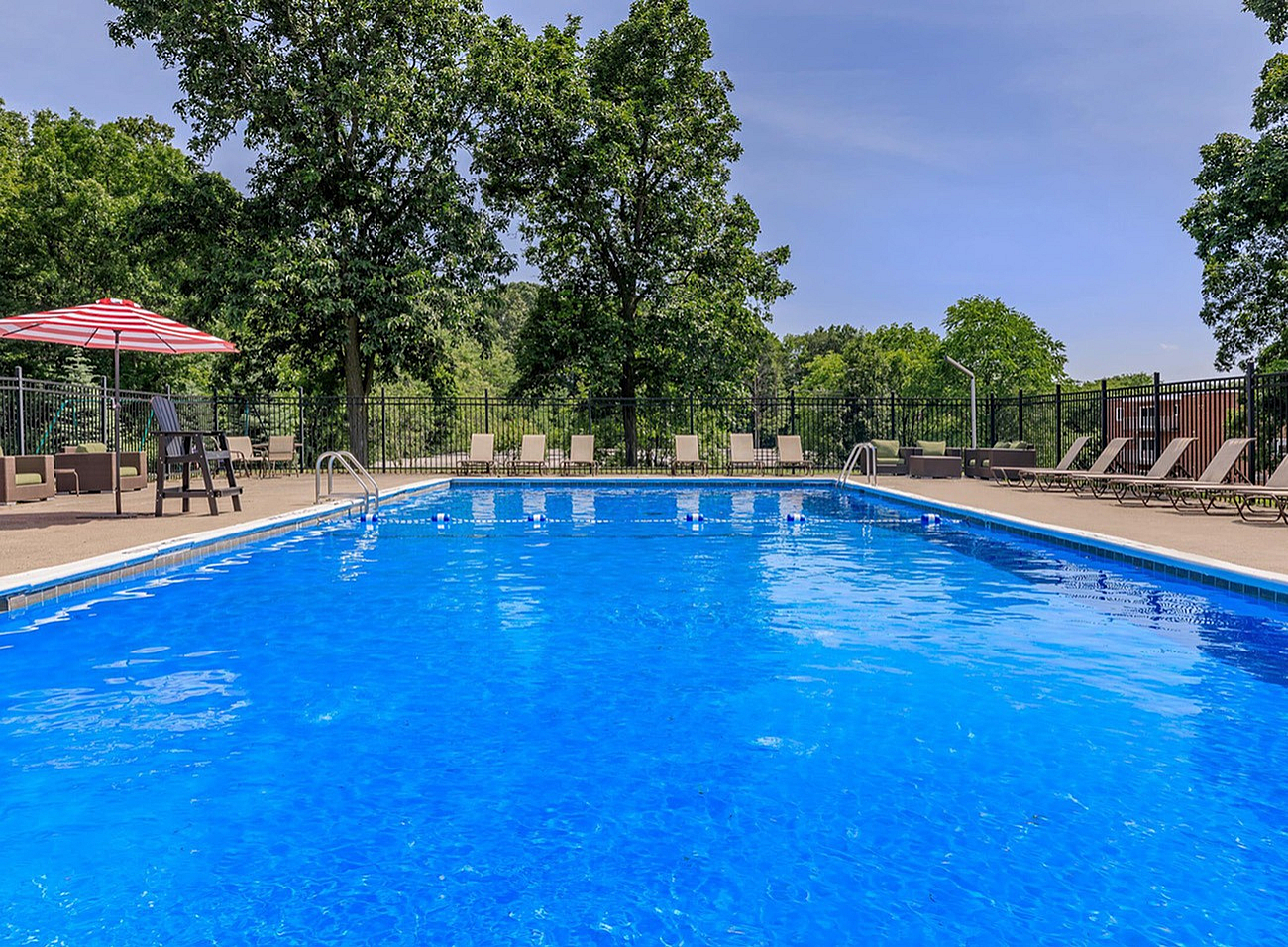 Inviting outdoor pool area with clear blue water, surrounded by lush greenery and sun loungers, perfect for relaxation.
